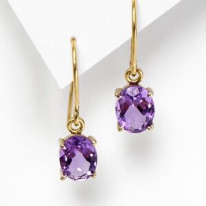 amatista y oro - Marisa Cano Gold drop earrings with oval purple gemstones set in four-prong gold settings on a white background