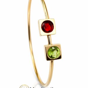 pulsera oro amarillo rigida - Marisa Cano Gold-tone bangle bracelet with two square settings holding a red gemstone on top and a green gemstone below against a white background.